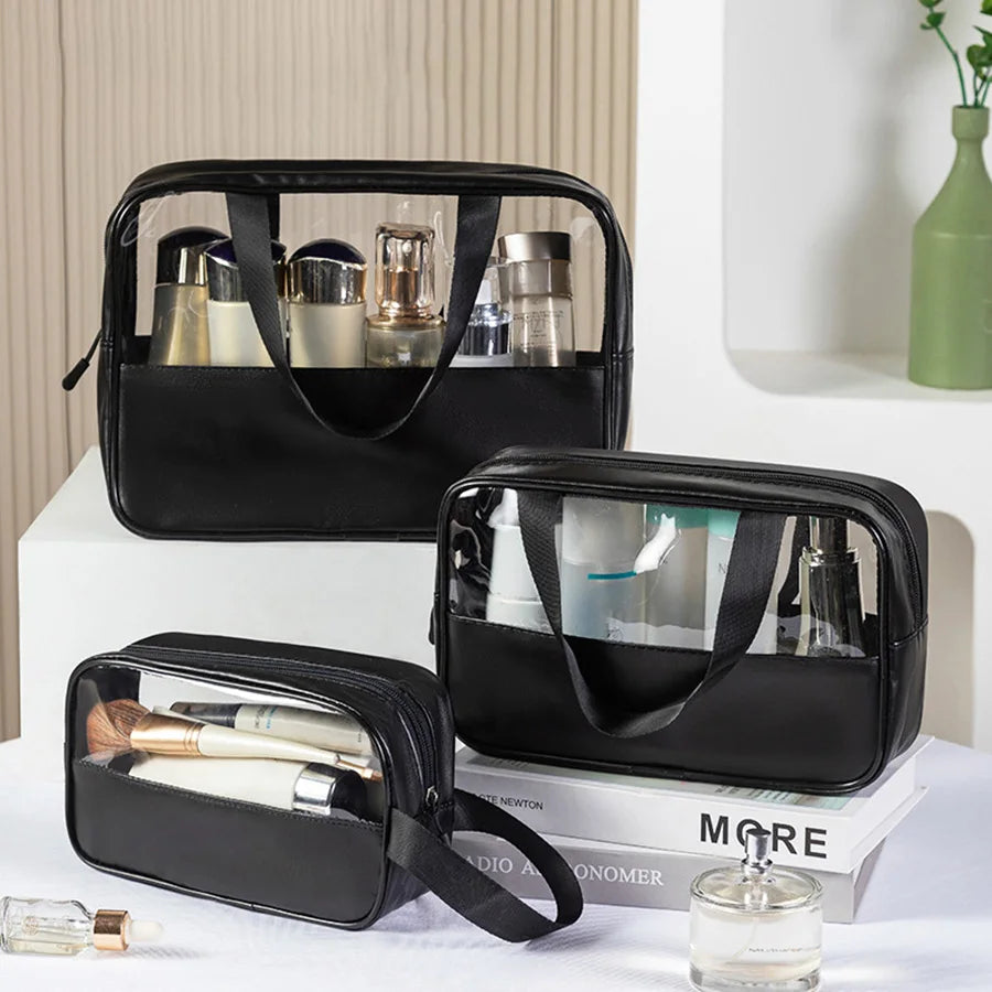 Set of three black matte translucent toiletry bags filled with skincare and makeup items, displayed on a vanity with books and decor